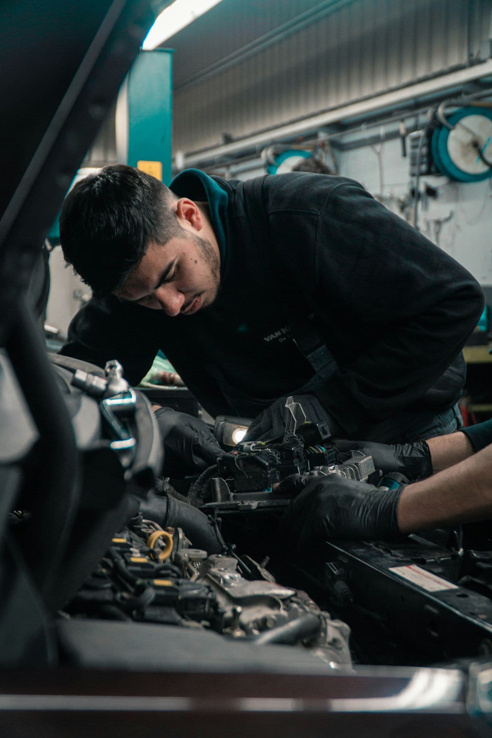 A mechanic leaning into an engine bay in a repair shop